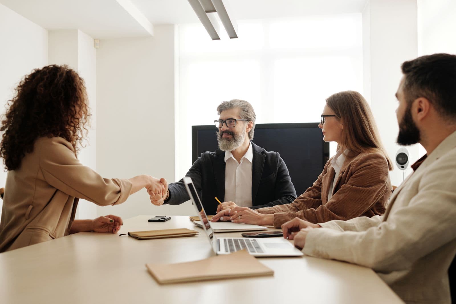 Entretien de recrutement autour d'une table, poignée de main entre deux personnes